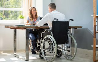 Man in wheelchair sitting at table meeting with a therapist
